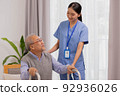 Asian nurse holding an elderly man with a walking stick for physiotherapy. 92936026