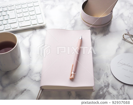 一張桌子圖像,上面有粉色筆記本和大理石桌子上的鍵盤 一張桌子圖像,上面有粉色筆記本和大理石桌子上的鍵盤 92937088
