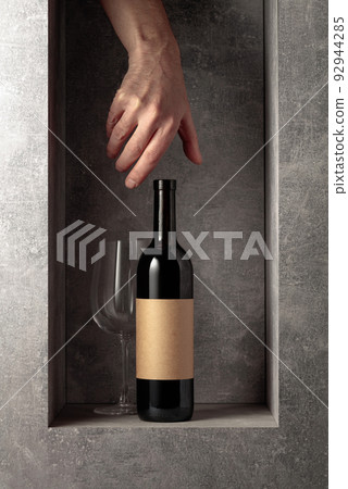 Hand reach for a bottle of red wine. 92944285