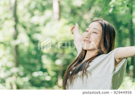 Japanese woman taking a deep breath at a summer resort (forest bathing, deep breathing, feeling good) 92944956