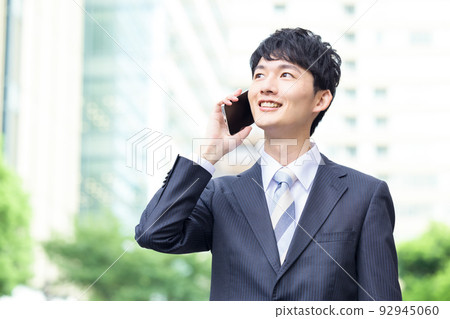 Business man walking outside with a smartphone 92945060