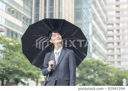 A man wearing a business suit and holding a parasol 92945394