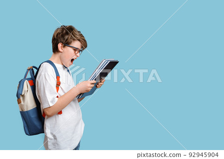 Surprised or outraged school boy looking at notepad or test grade Surprised or outraged school boy looking at notepad or test grade 92945904