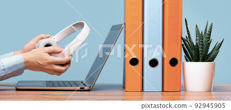 Laptop and hands with headphones on white desk Laptop and hands with headphones on white desk 92945905