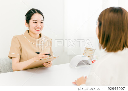 Manicurist having a hearing at a nail salon 92945907