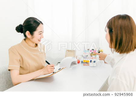 Manicurist having a hearing at a nail salon 92945908