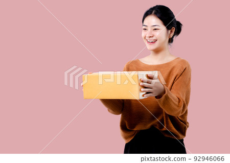 Happy Asian woman holding parcel box isolated over pink background. Happy Asian woman holding parcel box isolated over pink background. 92946066