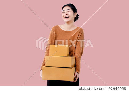 Happy Asian woman holding parcel box isolated over pink background. Happy Asian woman holding parcel box isolated over pink background. 92946068