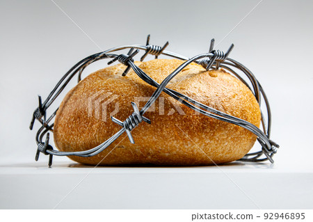 A loaf of round wheat bread wrapped with barbed wire. The concept of food crisis, food shortage 92946895