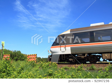 Diesel car passing through an unmanned railroad crossing on the embankment with a clear sky 92947236
