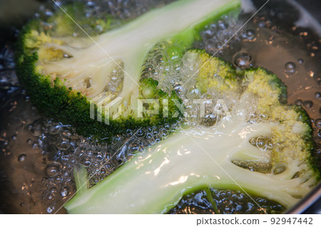 Broccoli inflorescences, cut lengthwise, are cooked in boiling water in a saucepan Broccoli inflorescences, cut lengthwise, are cooked in boiling water in a saucepan 92947442