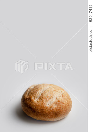 Round loaf of wheat bread on sourdough on a light background, vertical frame with space for text 92947452
