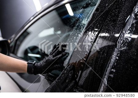employee of the car detailing studio protects the car body with a protective film employee of the car detailing studio protects the car body with a protective film 92948580