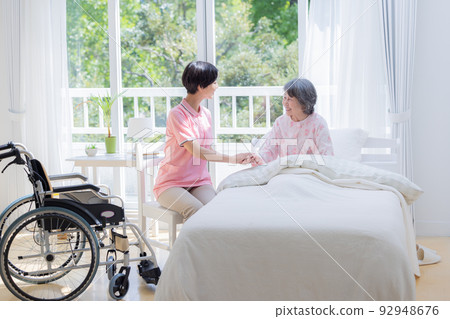 Nursing Caregiver helping seniors getting up from bed 92948676