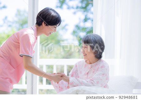 Nursing Caregiver helping seniors getting up from bed 92948681