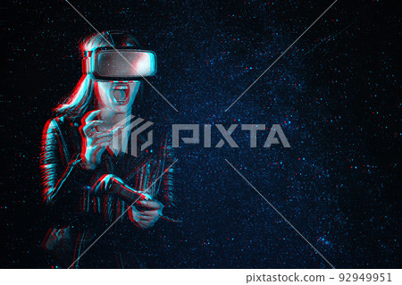 Girl plays modern computer games in virtual reality glasses. Emotional gamer with a joystick in his hands is immersed in world of augmented reality 92949951