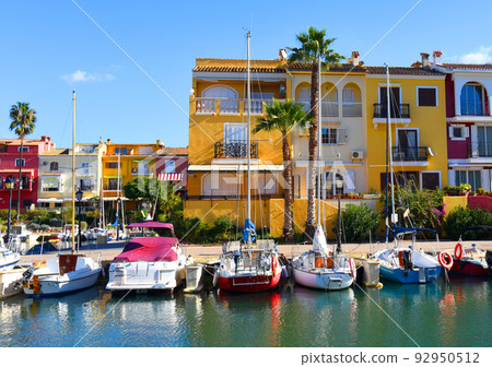 Yacht and fishing motorboat in yacht club. Colourful houses with apartments at coast Yacht and fishing motorboat in yacht club. Colourful houses with apartments at coast 92950512