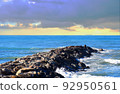 Breakwater with waves in sea. Waves at the stone pier. 92950561