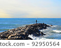 Fisherman on Masonry breakwater. A fisherman catches fish in the sea on a stone breakwater. 92950564