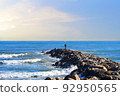 Fisherman on Masonry breakwater. A fisherman catches fish in the sea on a stone breakwater. 92950565
