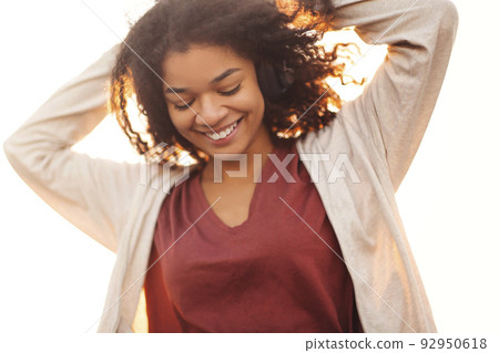 Full-length of young carefree african american woman jumping at rooftop in morning sunlight 92950618