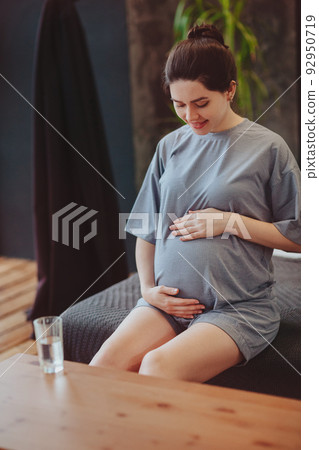 Healthy pregnancy. Young happy pregnant woman drinking clean water and gently touching belly Healthy pregnancy. Young happy pregnant woman drinking clean water and gently touching belly 92950719
