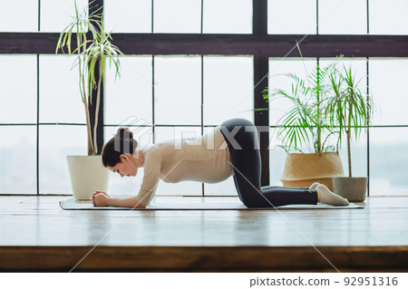 Meditation during pregnancy. Young calm tranquil pregnant woman doing yoga at home, meditating and practicing mindfulness 92951316