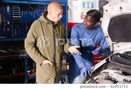 Owner of car explains the problem with car engine to mechanic of the car service 92951713