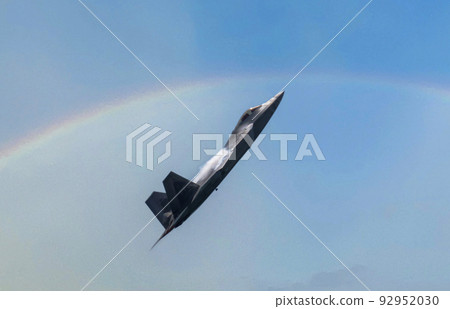 US Airforce F-22 Raptor climbing high with water vapor forming on the wings and a rainbow in the background 92952030