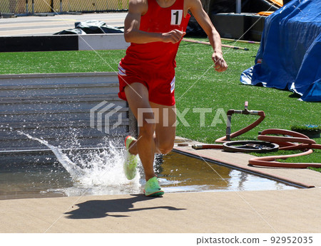 Runner with a number one on his uniform splashing as he exits the steeplchase 92952035