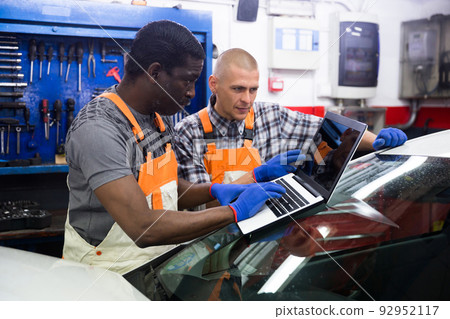 Mechanic and assistant working at service 92952117