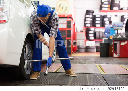 Professional auto mechanic screwing the wheel Professional auto mechanic screwing the wheel 92952131