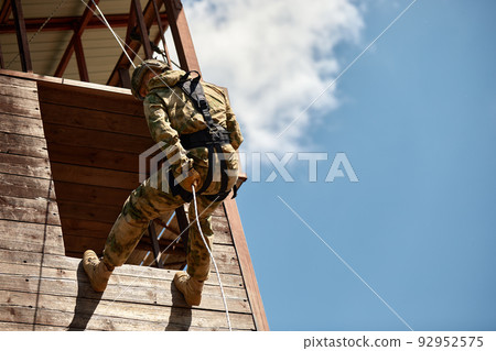 Military soldier climbing net during obstacle course in boot camp 92952575