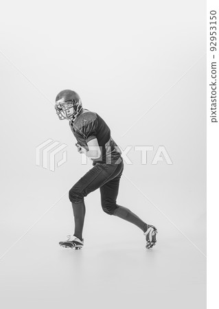 Portrait of concentrated young man, american football player in motion, action. Black and white photography. Centre-back 92953150