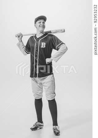 Portrait of cheerful young man, baseball player in uniform with bat posing. Black and white photography. Exhibition game Portrait of cheerful young man, baseball player in uniform with bat posing. Black and white photography. Exhibition game 92953232