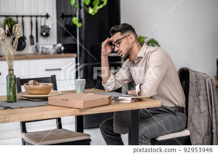 Sad man touching head sitting at table Sad man touching head sitting at table 92953946