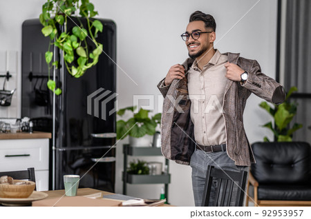 Man putting on jacket standing near table Man putting on jacket standing near table 92953957