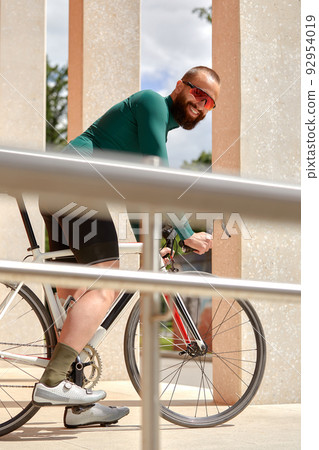 Caucasian handsome young man in protective helmet goes out for bicycle ride through city streets on blurred background. Cyclist male ride bike outdoors in urban. Caucasian handsome young man in protective helmet goes out for bicycle ride through city streets on blurred background. Cyclist male ride bike outdoors in urban. 92954019
