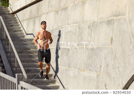 Young athlete man do morning run. Male runs up the stairs doing cardio exercises. 92954030