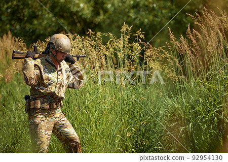 Portrait of fit military female holding weapon rifle in hands in river, posing alone. Confident strong athlete lady looking at side seriously. Attractive good-looking female in military gear Portrait of fit military female holding weapon rifle in hands in river, posing alone. Confident strong athlete lady looking at side seriously. Attractive good-looking female in military gear 92954130