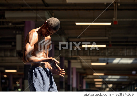 Handsome afro American sportman standing on the street while taking break after training. Black male having rest after workout Handsome afro American sportman standing on the street while taking break after training. Black male having rest after workout 92954169