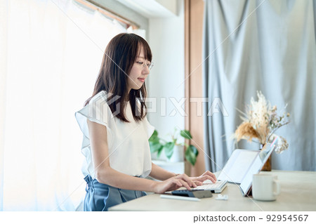 A woman wearing glasses and operating a tablet PC A woman wearing glasses and operating a tablet PC 92954567