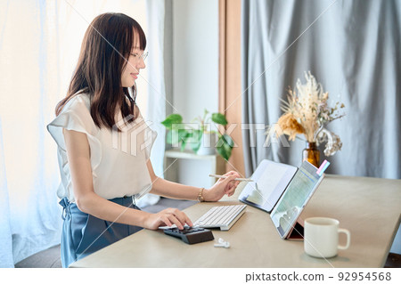 A woman wearing glasses and operating a tablet PC A woman wearing glasses and operating a tablet PC 92954568