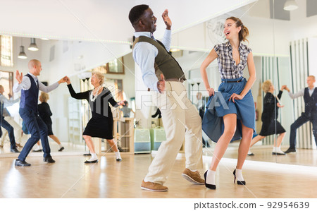Woman with african man practising charleston dancing Woman with african man practising charleston dancing 92954639