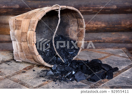 Barbecue charcoal obtained by pyrolysis, basket of wood coal overturned on table. 92955411