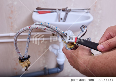 Plumbing work in toilet room, plumber installs new water faucet in home piping system. 92955435