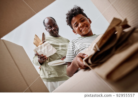 Low angle view of dad teaching his son to separate the garbage, they throwing paper in separate box 92955557