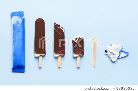 Chocolate covered ice cream on wooden stick at different states of consumption life cycle 92956055