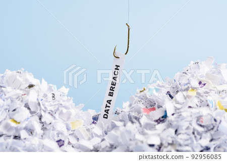 Word Data breach hooked on fishing hook pulled from pile of shredded documents on blue background Word Data breach hooked on fishing hook pulled from pile of shredded documents on blue background 92956085