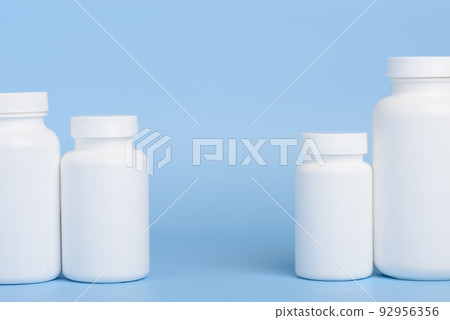 Blank white plastic bottles of medicine pills or supplements on blue background with copy-space  92956356
